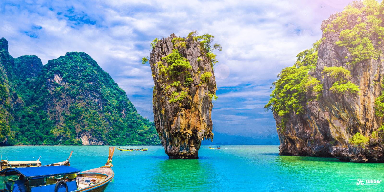 Iconic limestone karst of James Bond Island rising from emerald-green waters in Phang Nga Bay, surrounded by lush cliffs and longtail boats