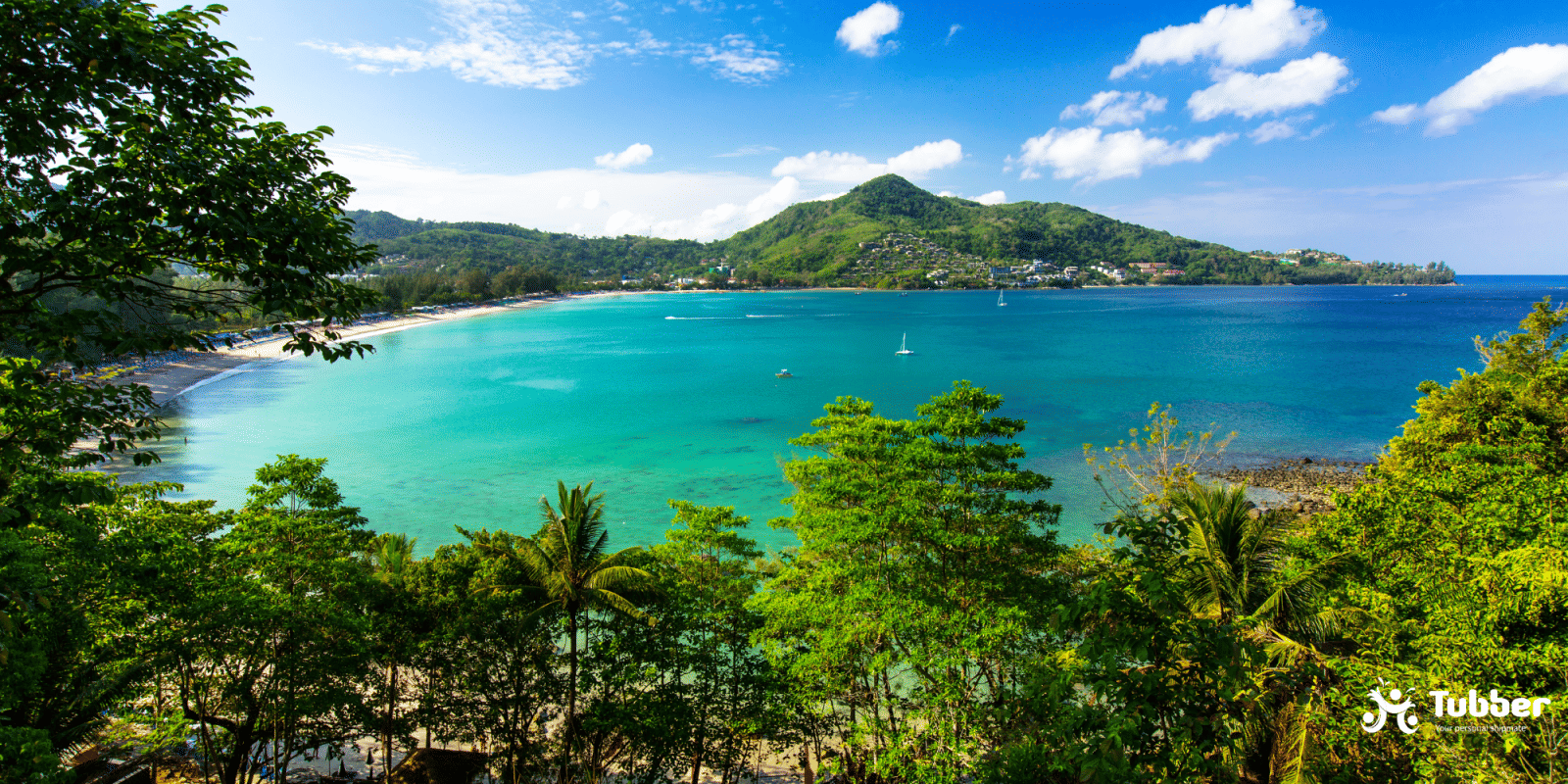 View over Kamala Bay showing calm, shallow turquoise waters, sandy beach, and lush green forest on Phuket Island