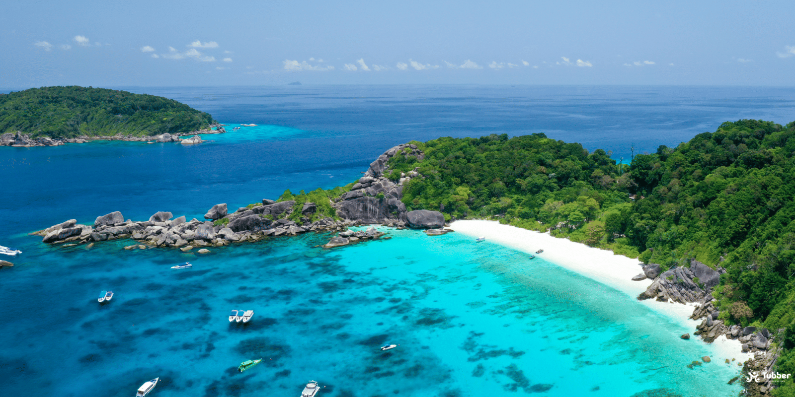 Crystal-clear blue water and granite rocks surrounding a white sand beach on the Similan Islands, a top diving destination in Thailand