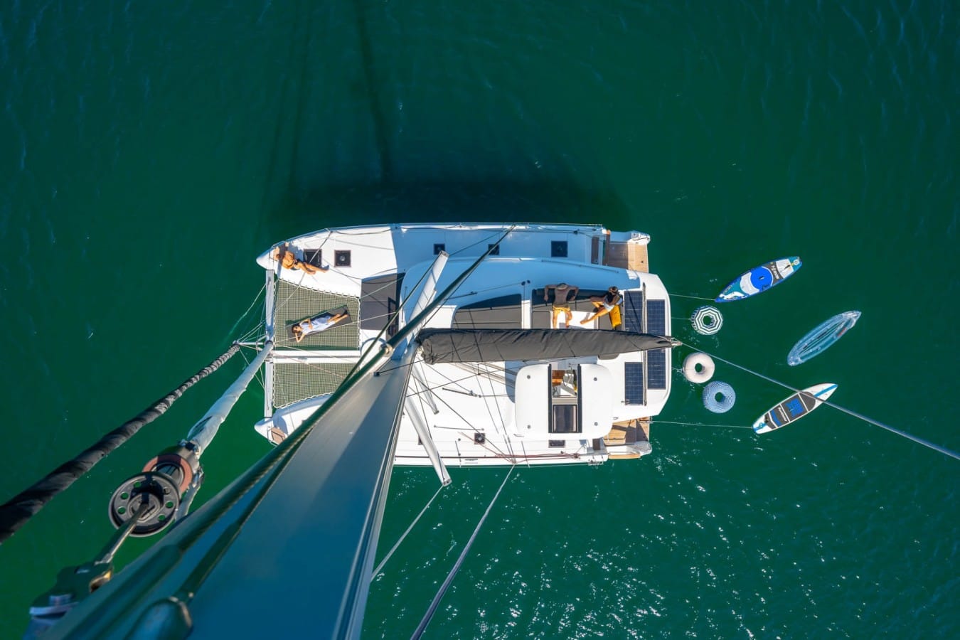 A view from the top of a catamaran with people laying on the sundeck.