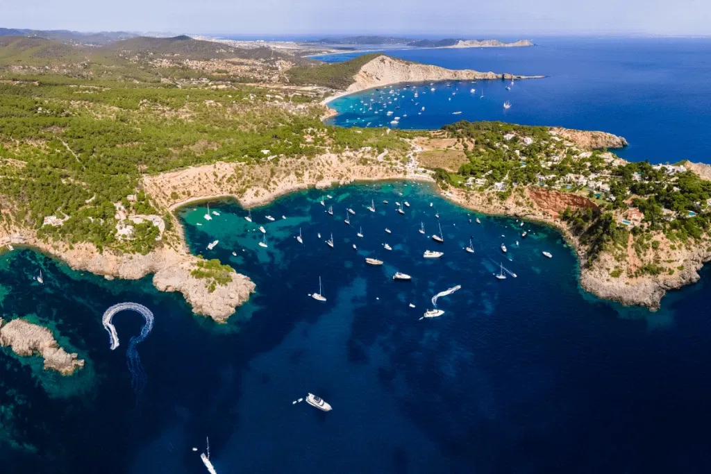 Porroig Ibiza: Luxusjachten in einer türkisfarbenen Bucht, umgeben von Hügeln