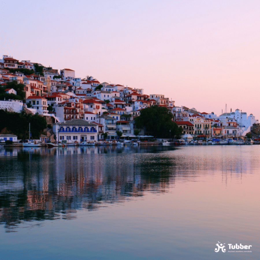Die Insel Skopelos in Griechenland, die ihren wunderschönen Hafen bei Sonnenuntergang zeigt, mit weißen Häusern, die den Hügel hinauf reichen.