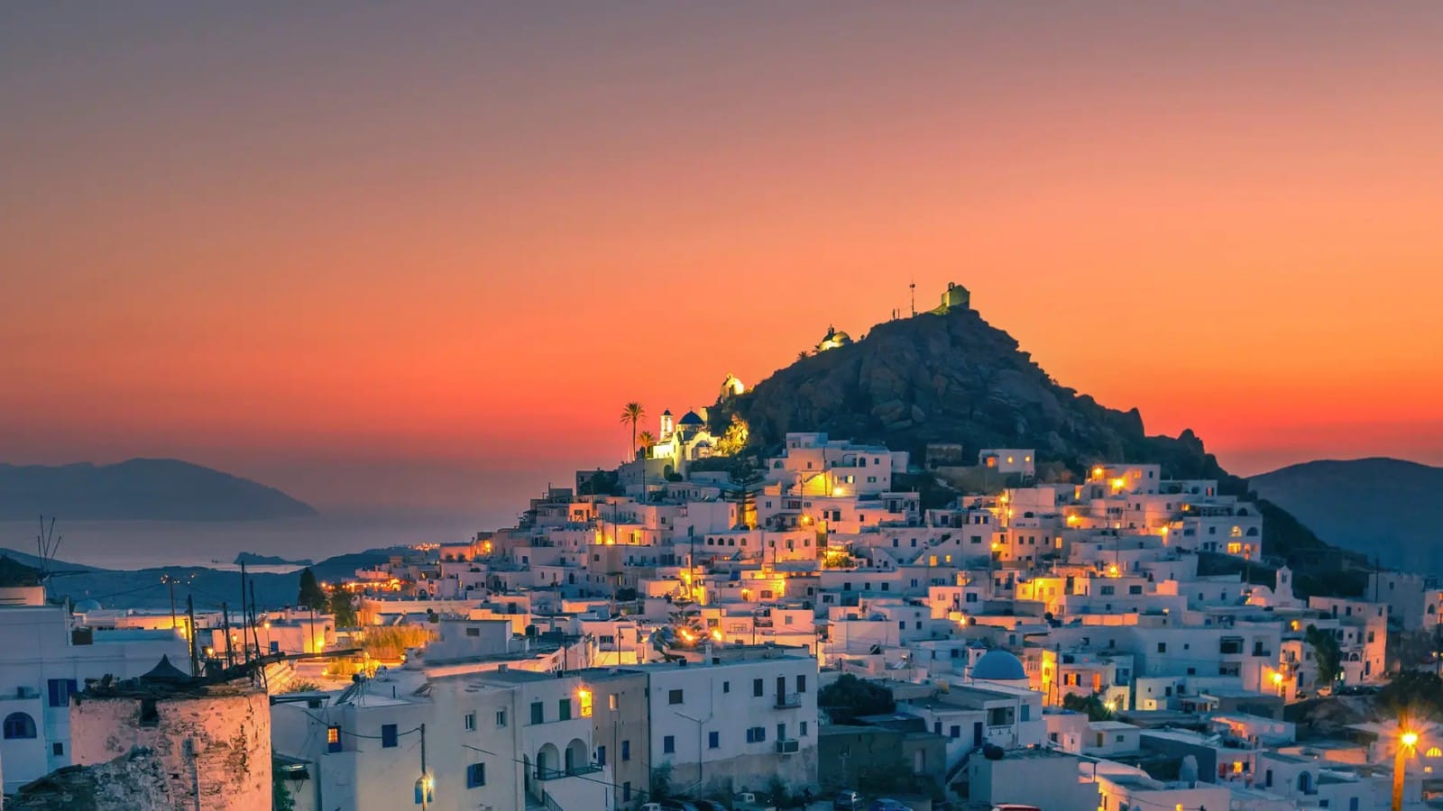 Ios in the evening with the sun setting behind a mountain on the island.