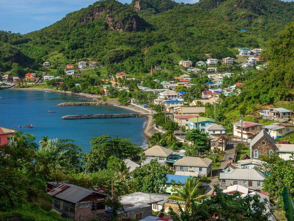 Der wunderschöne Hafen von St. Vincent in der Karibik, mit einigen Häusern und einem Berg im Hintergrund.
