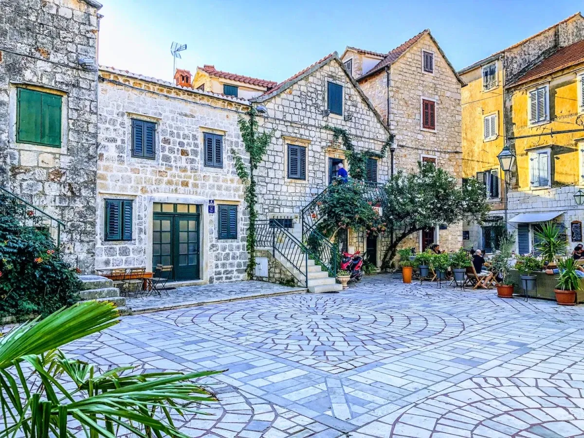 A plaza in Stari Grad, with old houses showing their beauty, and a cafe to the right.